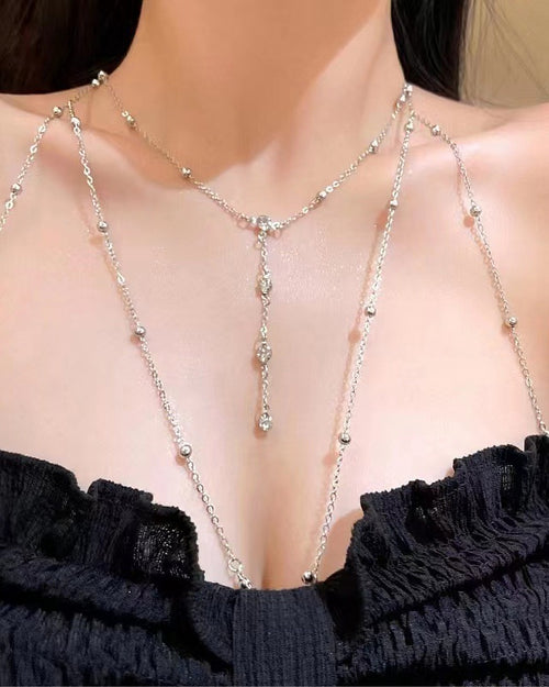 Chaîne de poitrine argentée à strass portée avec un bustier noir froncé