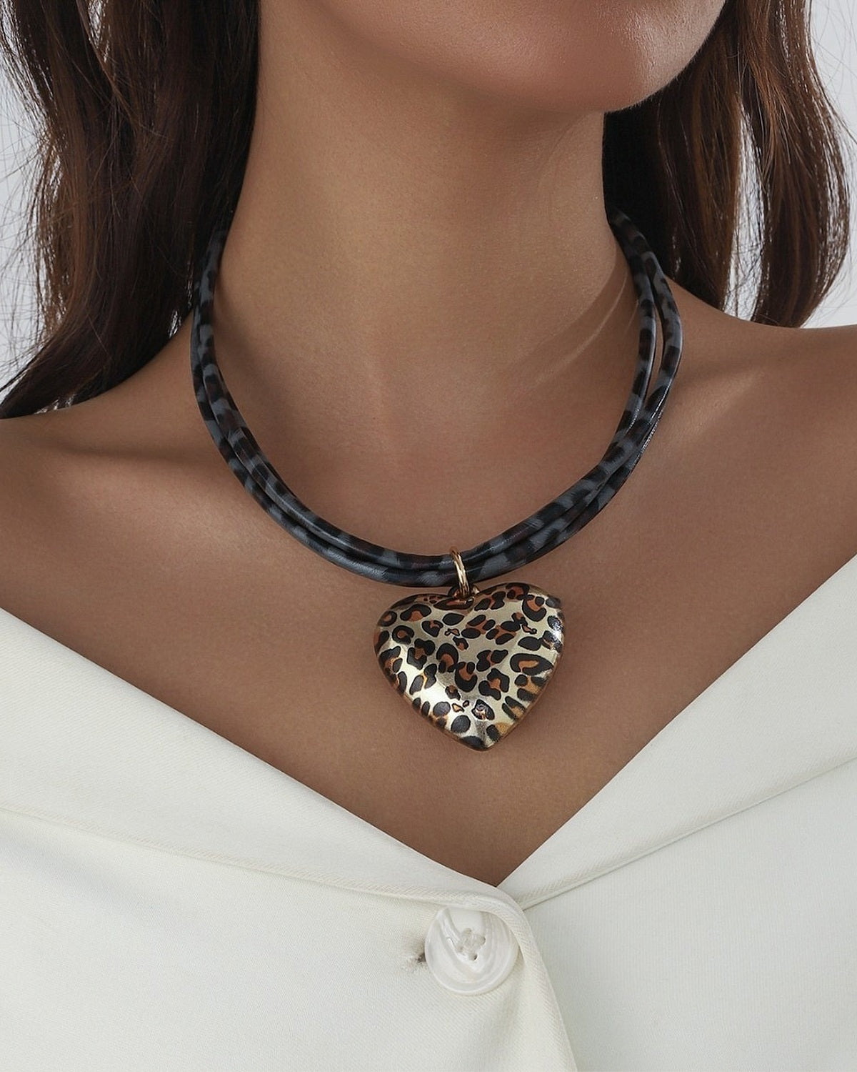 Collier cordon gris à pendentif cœur léopard porté avec une veste blanche
